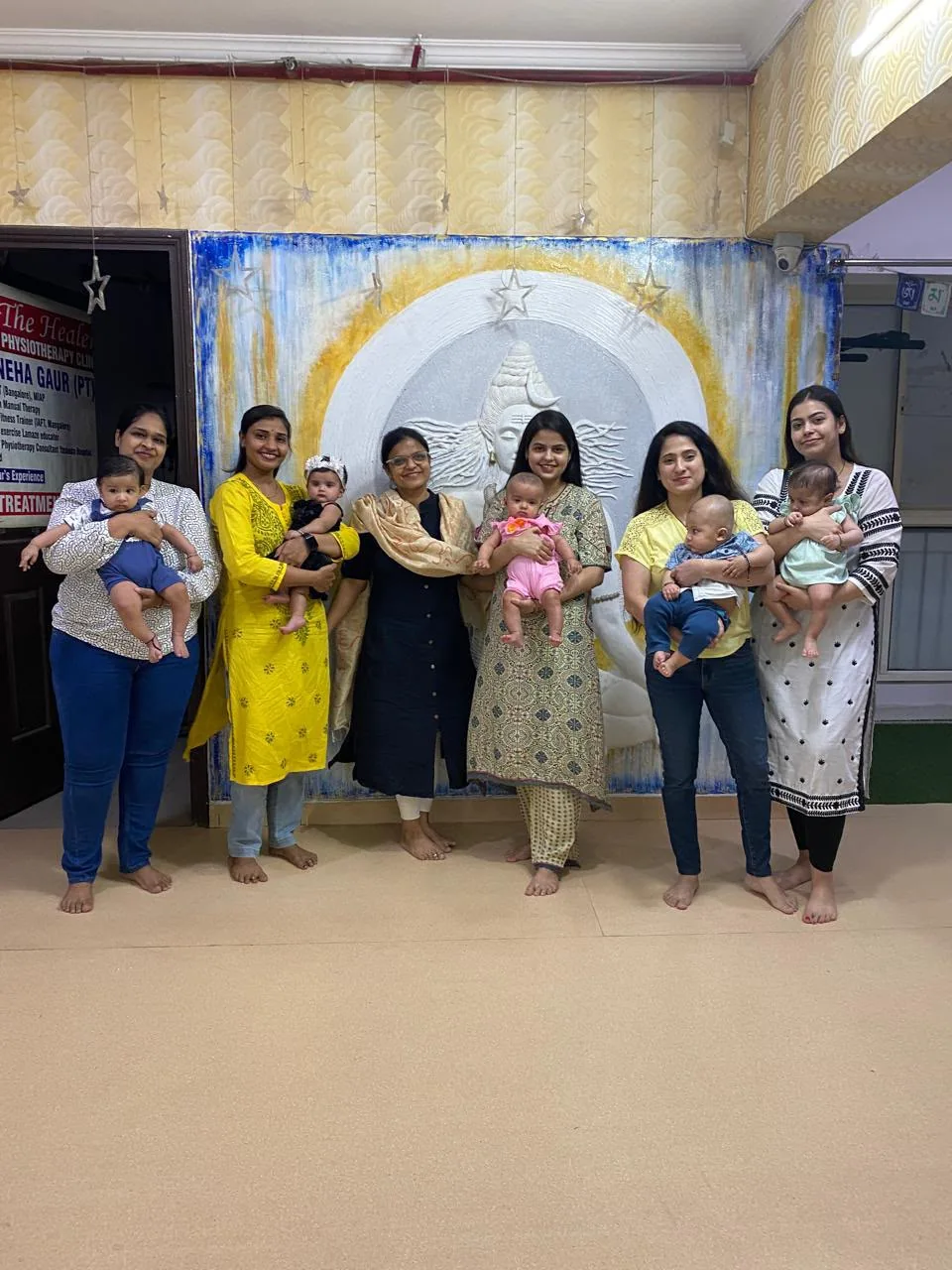 Dr. Neha Gaur with mothers and babies in a group photograph at her practice